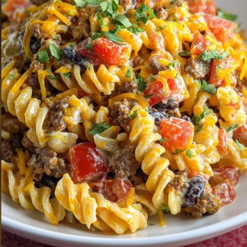 Colorful taco pasta salad topped with fresh ingredients in a bowl