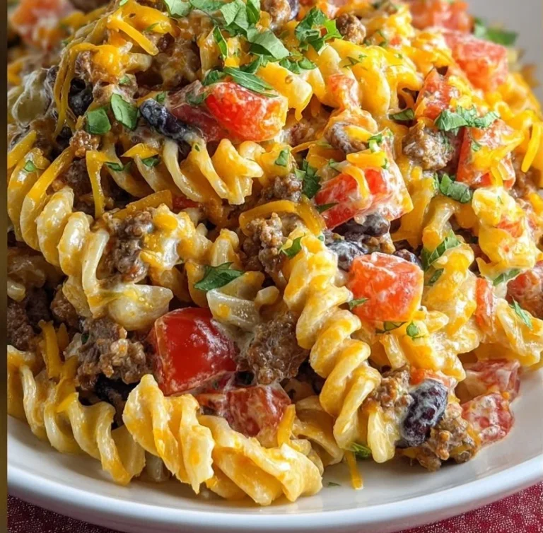 Colorful taco pasta salad topped with fresh ingredients in a bowl